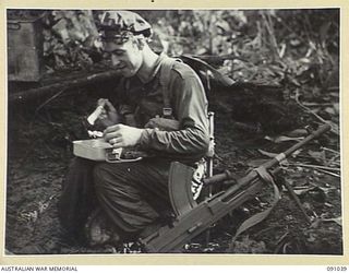 BOUGAINVILLE. 1945-04-17. PRIVATE A.F. EARLY, 14 PLATOON, C COMPANY, 24 INFANTRY BATTALION, BESIDE HIS BREN GUN ENJOYING A HOT STEW BROUGHT FORWARD BY COOKS DURING THE ATTACK AGAINST JAPANESE ..