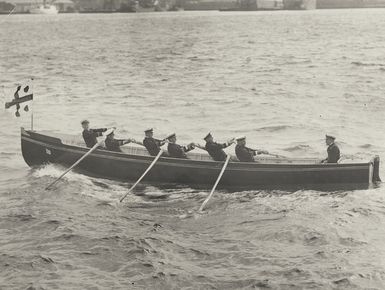 New Zealand naval personnel rowing a boat across a harbour