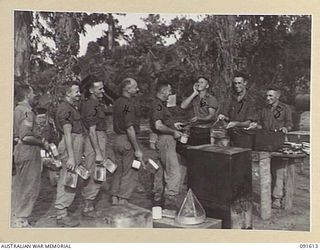 KARAWOP, NEW GUINEA. 1945-05-05. PRIVATE W.S.P. BONSER, COOK AT 2/1 INFANTRY BATTALION (6), YELLING "COME AND GET IT" TO THE TROOPS LINED UP FOR MESS PARADE. IDENTIFIED PERSONNEL ARE:- SERGEANT ..
