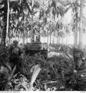 1942-12-28. PAPUA, GIROPA POINT AREA. AN AUSTRALIAN MANNED TANK FOLLOWED BY INFANTRYMEN IN ACTION LEADING TO THE FINAL ASSAULT ON BUNA. (NEGATIVE BY G. SILK.)