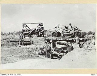 PAPUA, NEW GUINEA. 1942-08. AMERICAN ARMY ENGINEERS UNLOADING A "GRABALL" SCOOPFUL OF GRAVEL ON TO THE TRUCK WAITING UNDER THE BRIDGE. THE GRAVEL HAS BEEN SCOOPED FROM THE BED OF THE LOLOKI RIVER ..