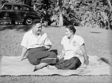 [A Pacific man and woman sitting on a mat on the ground]
