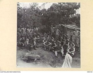 BRANDI, NEW GUINEA, 1945-09-07. MEMBERS OF 35 INFANTRY BATTALION GATHERED AROUND THE WIRELESS ON RACE DAY AWAITING RESULTS