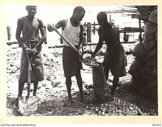 AITAPE BEACH HEAD, NEW GUINEA. 1944-11-25. NATIVES FILLING SAND BAGS WITH ROCKS. THESE WILL BE POSITIONED IN STEEL CAGES TO PROVIDE FOUNDATIONS FOR A PILE DRIVEN PIER CONSTRUCTED BY HQ 6 DIVISION ..
