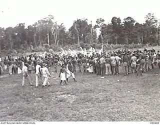 LAE, NEW GUINEA, 1945-12-25. INTERESTED SPECTATORS ATTENDING A SING-SING HELD AT THE MALAHANG NATIVE LABOUR COMPOUND TO CELEBRATE CHRISTMAS. MANY ALLIED AND AUSTRALIAN NEW GUINEA ADMINISTRATIVE ..
