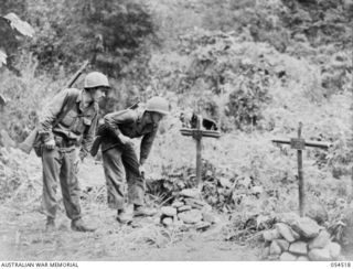 MUBO-SALAMAUA AREA, NEW GUINEA, 1943-07-21. PRIVATE FIRST CLASS D.J. COMMINS (LEFT) AND T.4 P. STEWART BOTH OF THE 1ST BATTALION, 162ND INFANTRY, UNITED STATES ARMY, STOP TO READ THE NOTICES ON THE ..