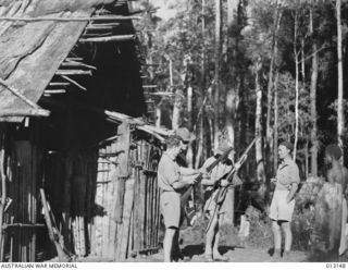 Skindewai, New Guinea. 28 August 1942. A group of Aussies inspect their rifles in camp. From left to right: Stan Tompkinson; Stuey Monroe, New Guinea Volunteer Rifles (NGVR); Private Roy O. Warren ..