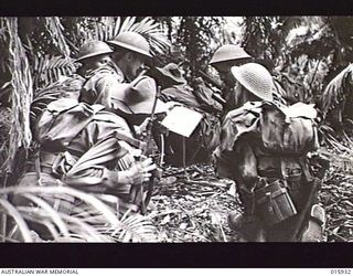 1943-10-06. NEW GUINEA. ATTACK ON LAE. THIS PLATOON OF A FAMOUS AUSTRALIAN BATTALION TOOK PART IN THE VICTORIOUS ADVANCE ON LAE. LT. JACK SCOTT OF BOGABILLA, N.S.W. WITH A MAP POINTS OUT THE ..