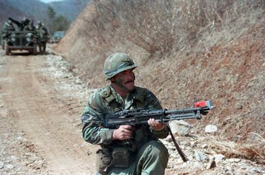 A soldier of the 227th Engineer Battalion, Hawaii Army National Guard, attached to the 1ST Battalion, 14th Infantry Division, 25th Infantry Division, Advances a mountain pass armed with an M60 machine gun during the joint US/South Korean Exercise TEAM SPIRIT '86