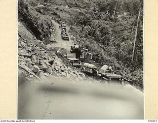 ZENAG, NEW GUINEA, 1944-02-27. A JEEP AND TRAILER CONVOY CONTINUING ALONG THE ROAD FOURTY EIGHT AND A HALF MILES FROM WAU AFTER THE SURFACE HAD BEEN CLEARED FROM A LANDSLIDE BY A D6 ANGLE DOZER ..