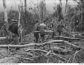 WEWAK AREA, NEW GUINEA, 1945-06-16. STRETCHER BEARERS CARRYING A WOUNDED MAN DOWN THE SIDE OF HILL 2, RECENTLY CAPTURED BY B COMPANY, 2/8TH INFANTRY BATTALION. THE TERRAIN GIVES AN IDEA OF THE ..