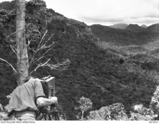 VX117252 CAPTAIN G. H. NICHOLSON, OFFICER COMMANDING, MILITARY HISTORY SECTION, ATTACHED HEADQUARTERS, NEW GUINEA FORCE, FILMING VISTAS FOR THE PRODUCTION, "RATS OF TOBRUK" FROM THE OWERS' CORNER ..