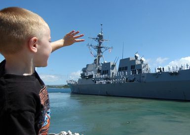 A young family member waves good-bye to a loved one onboard the US Navy (USN) Arleigh Burke Class Guided Missile Destroyer, USS CHAFEE (DDG 90) as she is underway leaving Pearl Harbor, Hawaii (HI), on her maiden deployment with the USN Nimitz Class Aircraft Carrier, USS NIMITZ (CVN 68) Carrier Strike Group (CSG) in support of the Global War on Terrorism (GWOT)