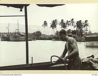 LABU POINT, LAE, NEW GUINEA. 1944-03-24. QX36166 CRAFTSMAN A. J. WHITE, A MEMBER OF THE 1ST WATERCRAFT WORKSHOP PICTURED AT WORK. LANDING BARGES AND SMALL CRAFT ARE BERTHED BESIDE THE UNIT'S ..