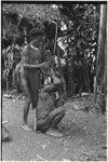 Pig festival, wig ritual, Tsembaga: man attaches headdress to another man's hair