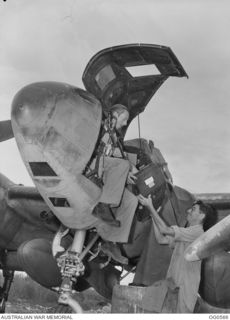 MILNE BAY, PAPUA. 1943-07-31. LEADING AIRCRAFTMAN (LAC) P. BLAND, GLADESVILLE, NSW, IS HANDING UP A FILM MAGAZINE TO LAC H. HARDIE, KOGARAH, NSW, TO BE LOADED INTO A CAMERA IN THE NOSE OF A P38 ..