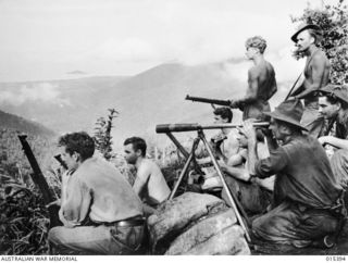 1943-08-04. NEW GUINEA. MUBO CAMPAIGN. AUSTRALIAN AND AMERICAN SOLDIERS WHO FOUGHT THE JAPS FROM NASSAU BAY TO MUBOM GAZE AT SALAMAUA. IN THE DIRECT LINE IT IS NOT SO VERY FAR AWAY FROM THESE ..