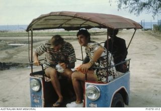 Returning from Nuku'alofa via local taxi service to the Australian High Commission.  Left to right Sappers Scott Noble and David 'Hoppy' Hooper in some locally purchased 'civvies'. This image ..