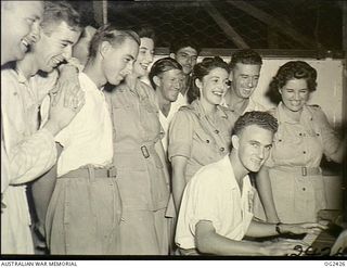 TOROKINA, BOUGAINVILLE ISLAND, SOLOMON ISLANDS. 1945-04-11. RED CROSS WORKERS JOIN IN COMMUNITY SINGING WITH CONVALESCENT RAAF PERSONNEL IN THE RECREATION HALL AT AN ARMY GENERAL HOSPITAL. SHOWN: ..