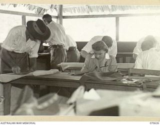 PORT MORESBY, PAPUA. 1944-02-25. MRS T. STEVENS (1), AUSTRALIAN RED CROSS SOCIETY MEMBER, WORKING IN THE SOCIETY'S HANDICRAFT SECTION AT THE 2/1ST GENERAL HOSPITAL