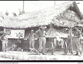 RABAUL, NEW BRITAIN, 1945-12-12. A CORNER OF THE SALVATION ARMY RECREATION HUT, AT 28TH INFANTRY BATTALION WITH A JAPANESE FIELD PIECE MOUNTED IN THE FOREGROUND