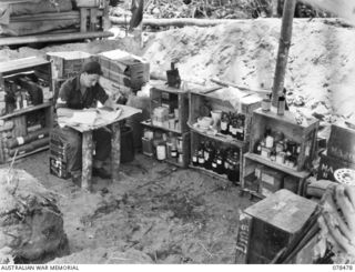 TAGESSI, BOUGAINVILLE ISLAND. 1945-01-17. NX203114 STAFF SERGEANT T. HAWKINS, DISPENSER, WORKING IN THE MEDICAL STORE OF THE ADVANCED DRESSING STATION "ADELE", 7TH FIELD AMBULANCE