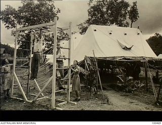 Port Moresby, New Guinea. 1944-05-28. Patients exercising on a wooden frame consisting of parallel bars and ladders outside the Physiotherapy Department, 2/1st Australian General Hospital under the ..