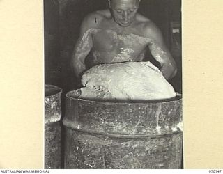 DUMPU, NEW GUINEA. 1944-01-05. NX136150 STAFF SERGEANT A.W. HUEGILL (1) OF THE 15TH INFANTRY BRIGADE BAKERY, LIFTING DOUGH FOR ROLL MAKING. BREAD ROLLS ARE FOUND MORE SUITABLE FOR JUNGLE WARFARE AS ..