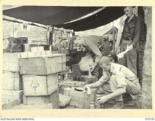 SIAR, NEW GUINEA. 1944-08-09. Q22370 PRIVATE J.J. PURCELL (1); Q22419 PRIVATE J. WATSON (2) AND Q21901 WARRANT OFFICER 2 M. OLSEN, UNIT CATERER (3), BREAKING UP RATIONS INTO COMPANY LOTS IN THE ..