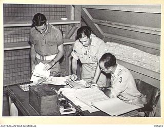 LAE AREA, NEW GUINEA. 1945-08-31. MEMBERS OF THE ARMY NEWSPAPER, GUINEA GOLD, WORKING IN THE ADMINISTRATIVE OFFICE WHICH CONTROLS DISTRIBUTION. THEY ARE PRIVATE R. IVERS, CLERK (1); WARRANT OFFICER ..