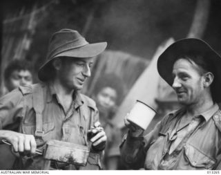 OWEN STANLEY RANGES, NEW GUINEA. C. 1942-09-01. CORPORAL H. G. EVANS AND SGT. L. R. MARTORANA OF THE A.M.F. AT A NATIVE VILLAGE SHORTLY AFTER THEIR UNIT HAS CLASHED WITH THE JAPANESE IN THE KOKODA ..