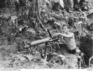 BOUGAINVILLE ISLAND, 1945-01-20. QX41326 PRIVATE G.F. ATWELL, 42ND INFANTRY BATTALION CHECKING OVER THE MECHANISM OF HIS MACHINE GUN IN HIS WEAPON PIT AT MAWARAKA