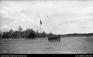 Honor guard of seven men with rifles, near a flag