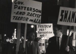 White and African American protesters carrying signs at a demonstration against John Patterson and segregation, possibly in downtown Honolulu, Hawaii.
