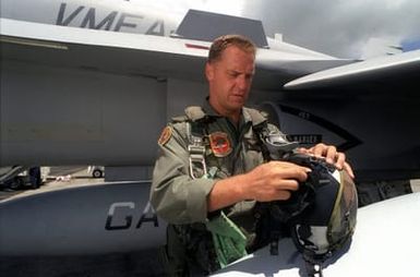 US Marine Corps pilot MAJ Dwight Schmidt of VMFA-142 based at NAS Atlanta, Georgia inspects his survival equipment prior to departing on a mission during exercise RIMPAC'98. Behind him is the F/A-18 Hornet fighter