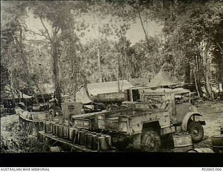 Gusika, Finschhafen area, New Guinea. 1944-03. Trucks and tents set up at the camp of 17 Field Hygiene Company. In the foreground are knapsack sprays carrying a special oil. They are used to spray ..