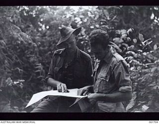 WAREO, NEW GUINEA. 1943-12-09. VX7410 LIEUTENANT D. C. LAWRIE DCM, OF CAMBERWELL, VIC (LEFT) STUDYING A MAP WITH VX50364 CAPTAIN H. GRAY OF MALVERN, VIC, OFFICER COMMANDING C COMPANY, 2/23RD ..