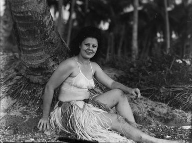 [Portrait of a Polynesian woman sitting at the base of a palm tree]