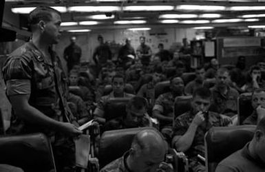 A warrant officer stands to relay some information during a pre-operation briefing for the officers of Marine Medium Helicopter Squadron 261 (HMM-261) in the squadron ready room aboard the amphibious assault ship USS SAIPAN (LHA 2). The SAIPAN is on station off the coast of Liberia for Operation Sharp Edge