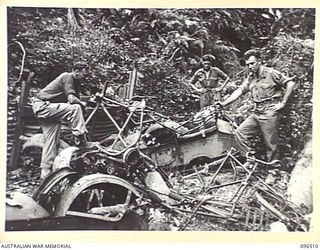 RABAUL, NEW BRITAIN, 1945-09-11. MEMBERS OF 29/46TH INFANTRY BATTALION EXAMINE A DUMP OF DISCARDED PARTS OF JAPANESE BICYCLES AND MOTOR CYCLE COMBINATIONS IN THE TUNNEL HILL ROAD AREA. THE TROOPS ..