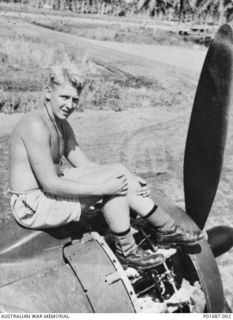 MILNE BAY, PAPUA, 1943-05. IAN BEAUREPAIRE, AN ARMOURER WITH NO. 100 SQUADRON RAAF, SITTING ON AN ENGINE COWLING OF ONE OF THE SQUADRON'S AIRCRAFT, BRISTOL BEAUFORT BOMBER NO. A9-227, AS HE WORKS ..