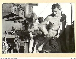 ALEXISHAFEN, NEW GUINEA. 1944-05-15. PETTY OFFICER R.S. IMPEY (1), WORKING AT HIS REMUNERATIVE HOBBY OF MAKING SANDALS FROM JAPANESE LEATHER HIDE FOR FELLOW CREW MEMBERS ABOARD HMAS KAPUNDA. HE CAN ..