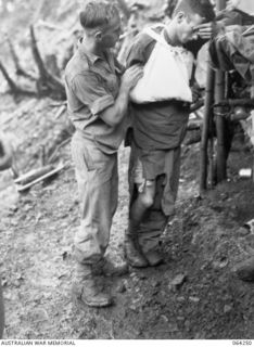 FINISTERRE RANGES, NEW GUINEA. 1944-01-23. QX2102 PRIVATE R.E. SPARKS, REGIMENTAL AID POST ORDERLY (1) ATTENDING TO QX53106 PRIVATE A.R. BIRCH (2) A WOUNDED SOLDIER OF THE 2/9TH INFANTRY BATTALION