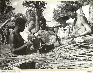 1943-07-26. NEW GUINEA. MRS VERA MORTON, THE LAST WOMAN TO BE EVACUATED FROM NEW GUINEA, IS NOW BACK AGAIN AS A RED CROSS WORKER. HERE SHE IS WITH SOME OF THE LADS SHE HAS TAUGHT THE ART OF MAKING ..