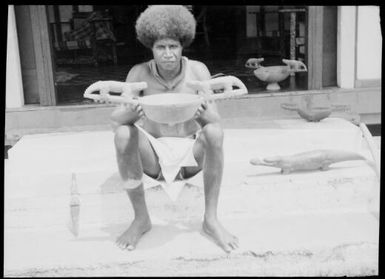 Seated man holding bowl with elaborate carved handles, Awar [?], Sepik River, New Guinea, 1935 / Sarah Chinnery