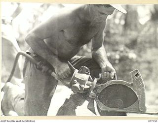 JACQUINOT BAY, NEW BRITAIN. 1944-11-20. QX38832 SAPPER J.D. MCCRACKEN, 9TH FIELD COMPANY, USING A COMPRESSED AIR SAW TO CUT TIMBER ON A NEW BRIDGE BEING BUILT BY THE UNIT IN THE PALMALMAL ..