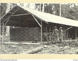 LAE, NEW GUINEA. 1944-03-29. MEMBERS OF THE 103RD FIELD AMMUNITION DEPOT STACK 25 POUNDER SHELLS IN CORRECT ORDER. LEFT TO RIGHT: VX121188 PRIVATE L. C. GLEDHILL; NX111959 SERGEANT J. W. LYNCH; ..