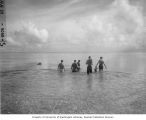 Group of scientists wading out on to the reef to examine location for spreading fish poison at Namu Island, 1947