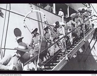 SYDNEY, NSW. 1946-05-16. LOADED DOWN WITH GEAR, LONG SERVICE PERSONNEL FILE DOWN THE GANGPLANK FROM THE TROOPSHIP CANBERRA, AFTER IT HAD BERTHED AT CIRCULAR QUAY FROM RABAUL