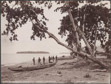 Six men standing next to a canoe on a Buala beach, with island of Kumaigola in background, Solomon Islands, 1906 / J.W. Beattie
